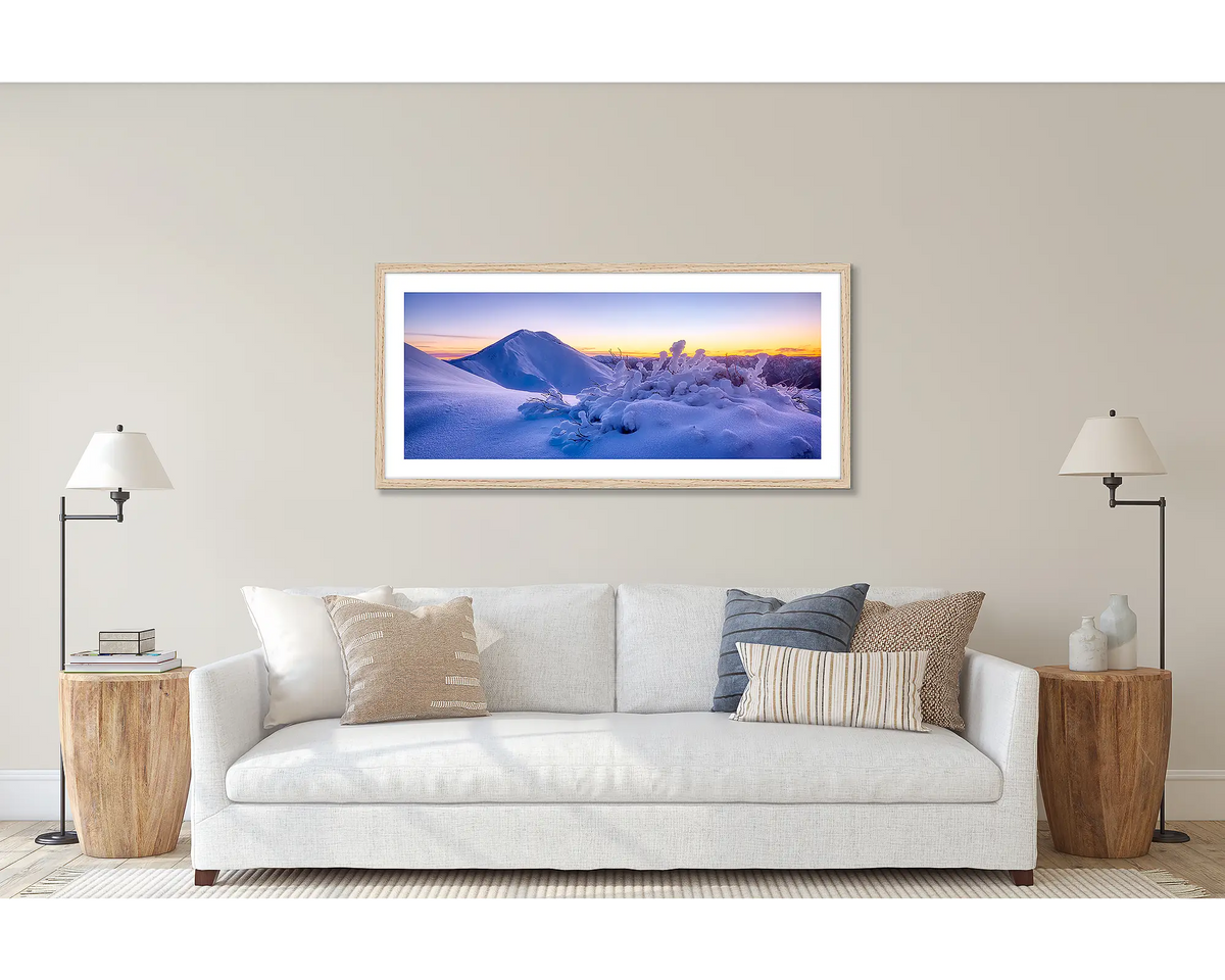 Feathertop Dawn. Wall art print of a winter sunrise over Mount Feathertop, framed with a Tasmanian Oak frame and hung above a couch. 