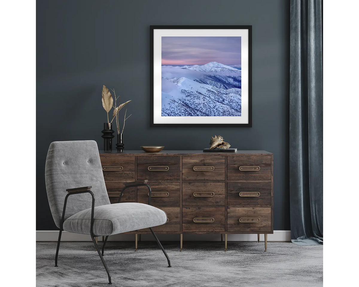 Feathertop Dusk. Wall art print with black frame of Mount Feathertop covered in snow, hung in a room with dark walls.