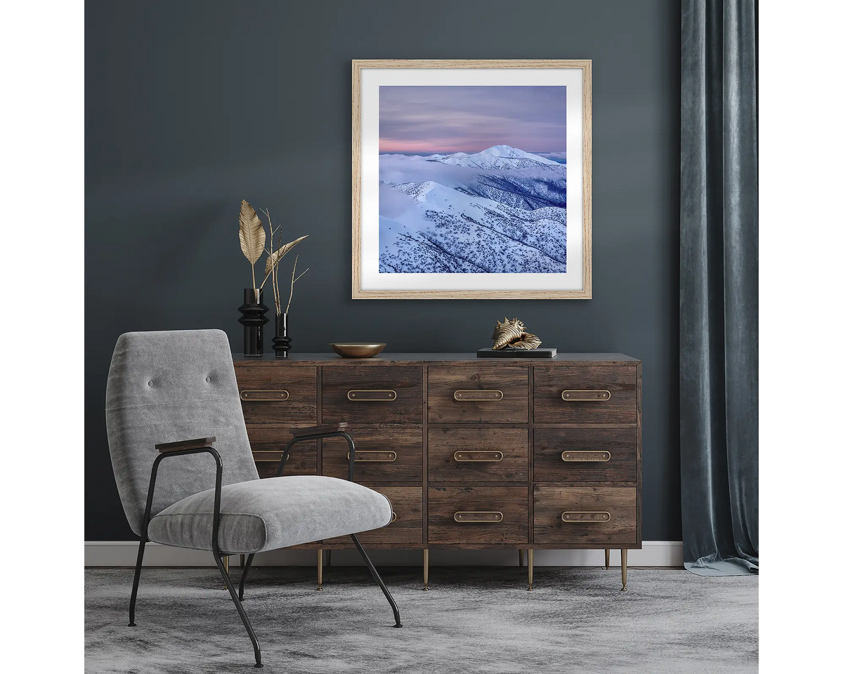Feathertop Dusk. Wall art print with timber  frame of Mount Feathertop covered in snow, hung in a room with dark walls.