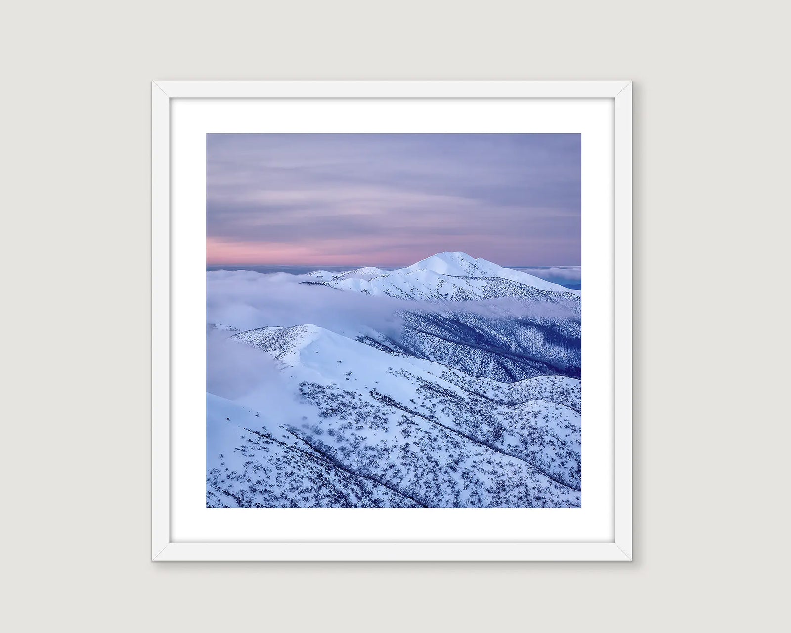 Framed photographic wall art print of fog at sunset, swirling around Mount Feathertop, covered in snow. 