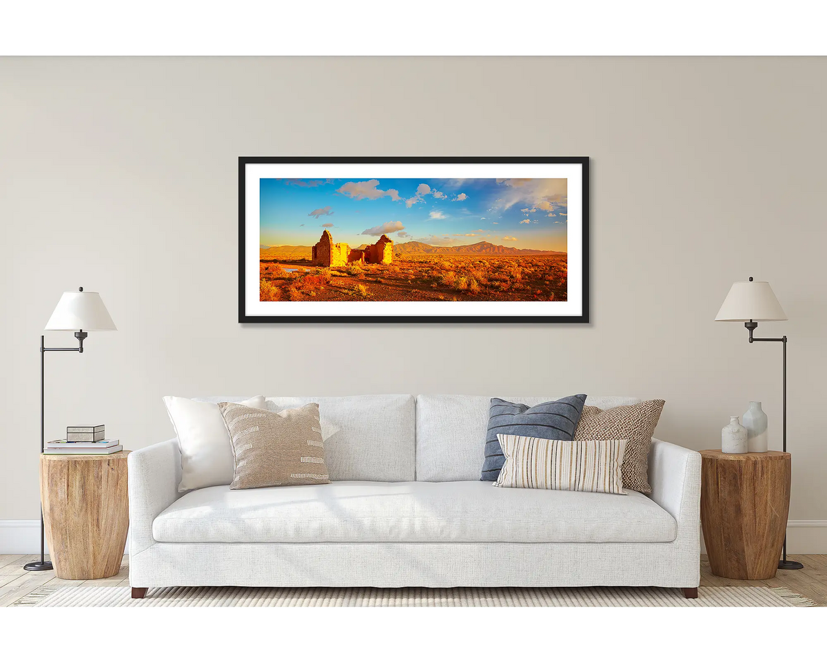 Flinders Ruins. Wall art print of a sunset in the Flinders Ranges, framed with a black frame and hung above a couch. 