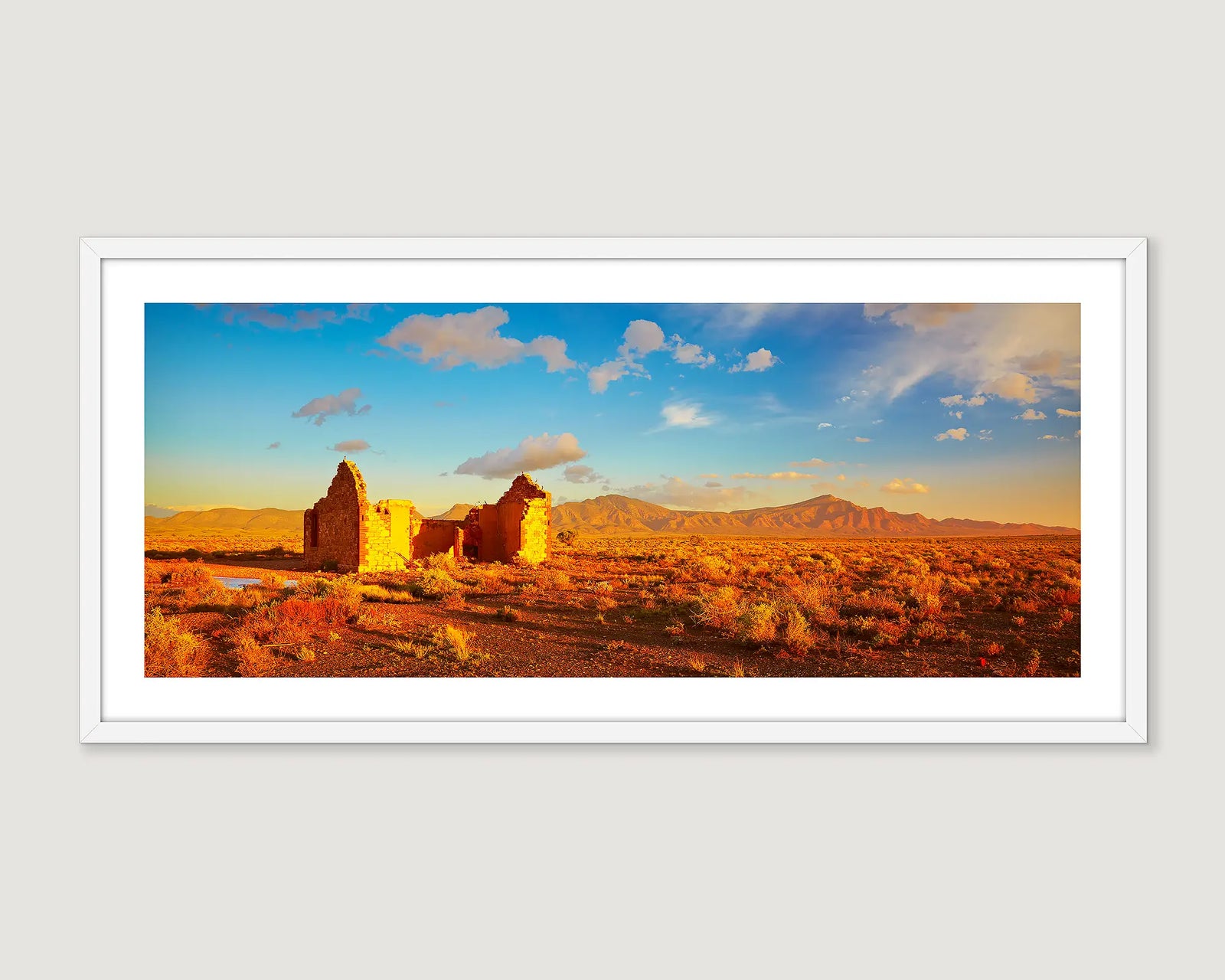 Framed photograph of ruins of an outback pioneer settlement with the Flinders Ranges in the background.