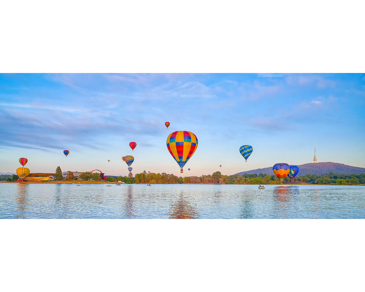 Floating. Colourful hot air balloons over a Lake Burley Griffin with a Black Mountain in the background.
