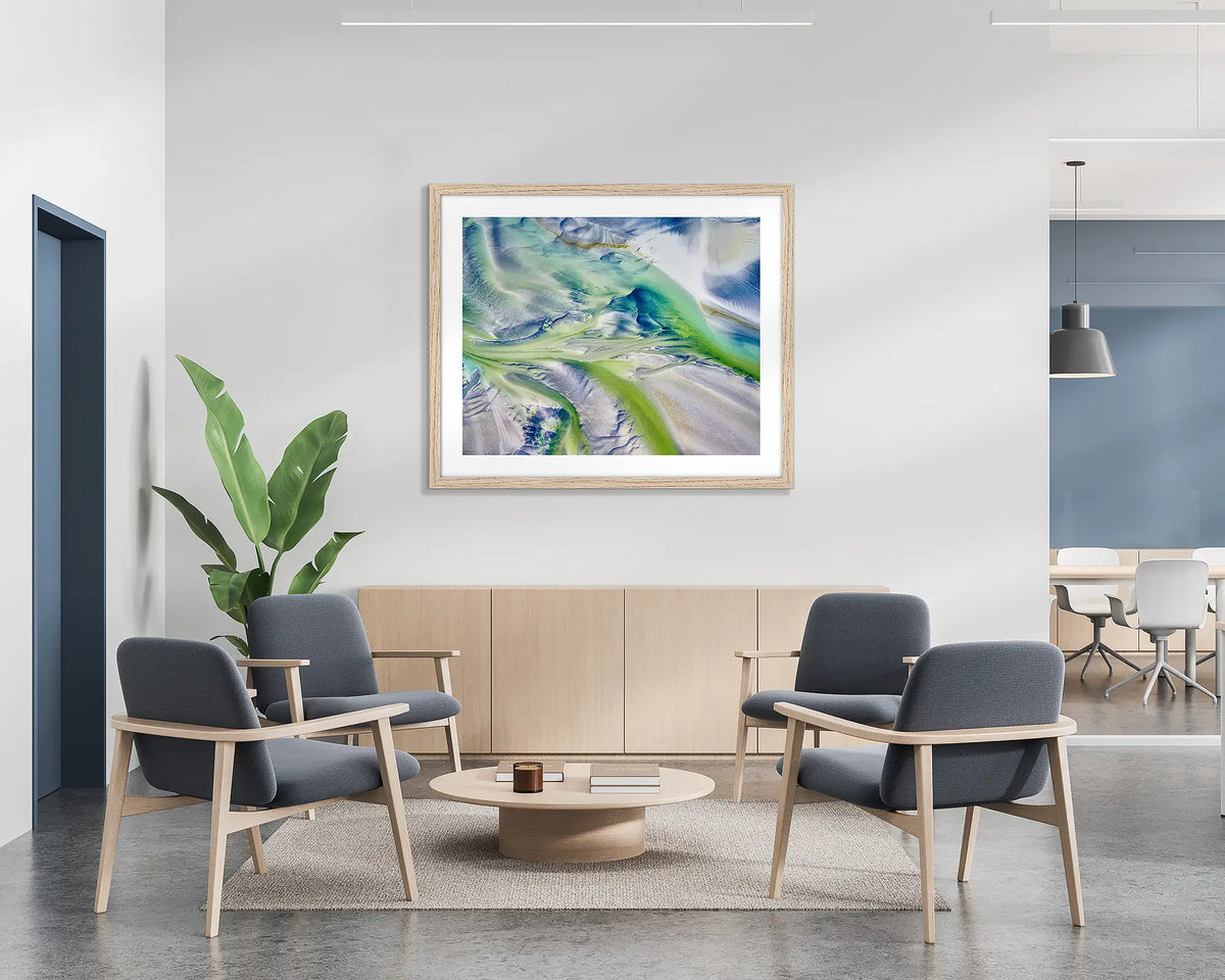Flow. Aerial abstract wall art print with a Tasmanian Oak frame, hung on the wall of a waiting area.