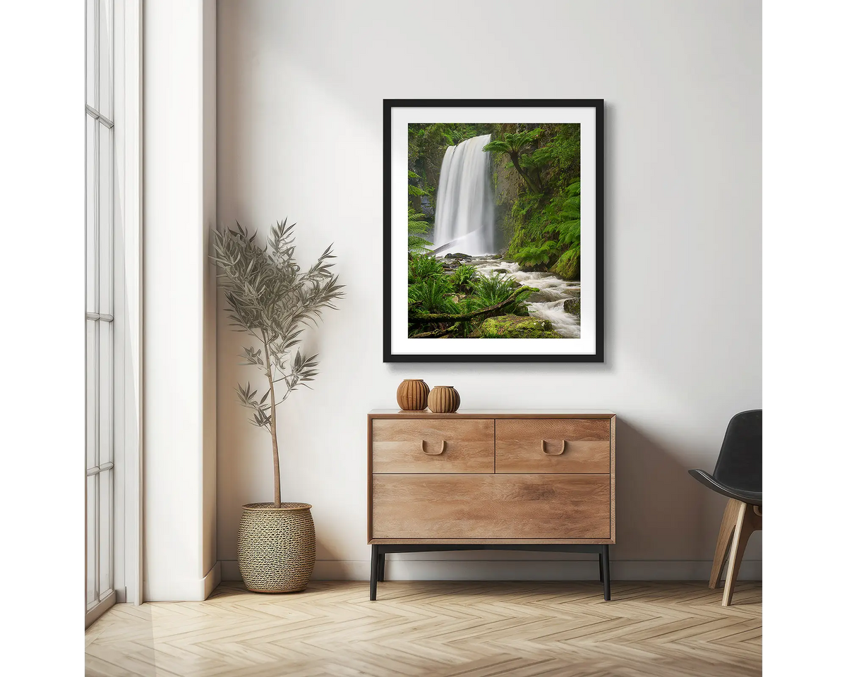 Forest Veil. Wall art print of Hopetoun Falls, framed with a black frame and hung on an apartment wall above a side table. 