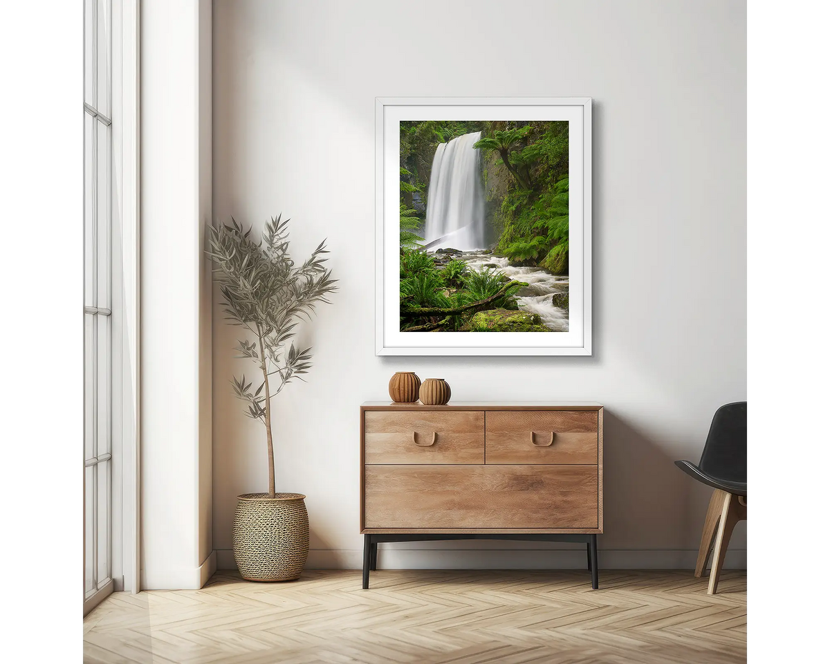 Forest Veil. Wall art print of Hopetoun Falls, framed with a white frame and hung on an apartment wall above a side table. 