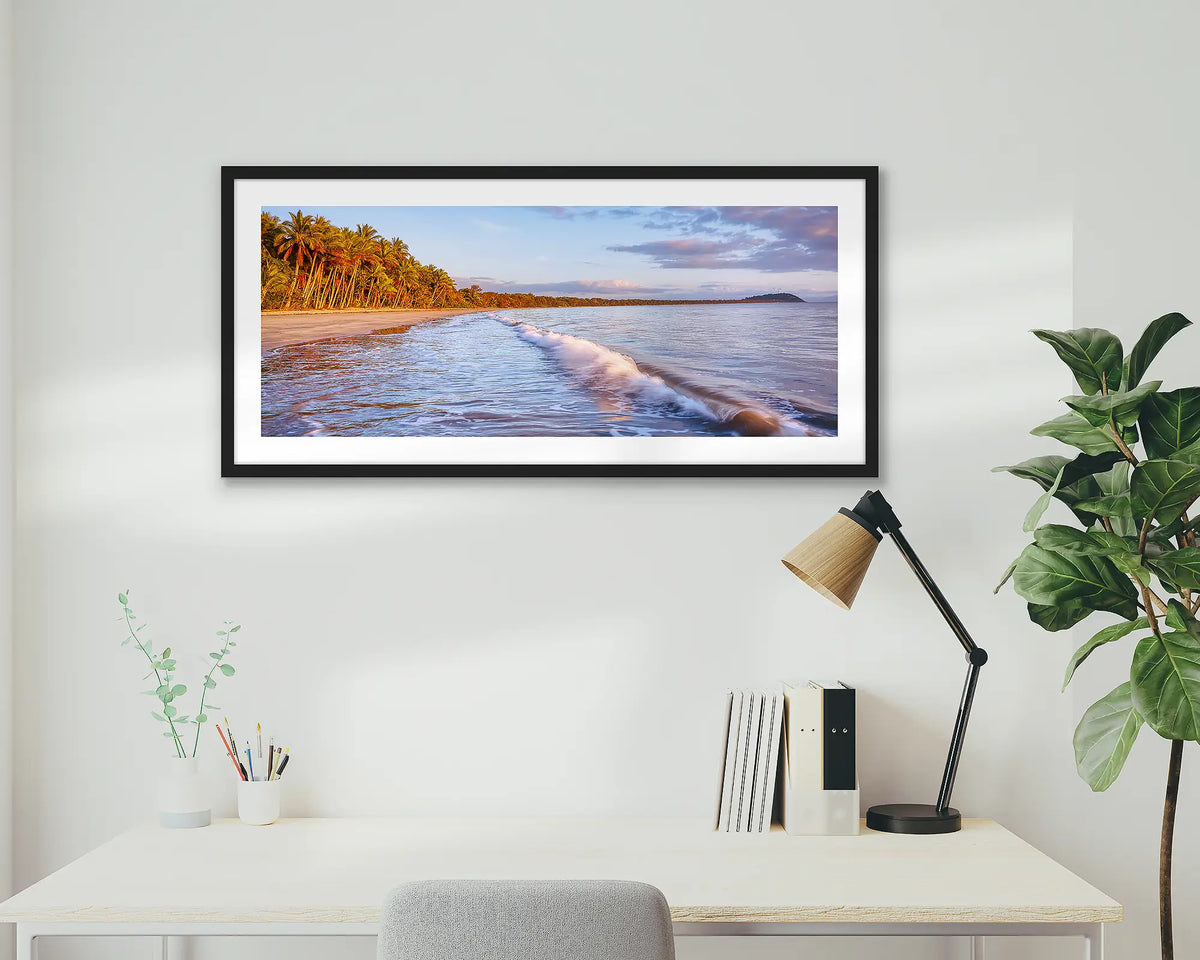 Four Mile Sunrise. Framed wall art print of Four Mile Beach, Port Douglas, with a black frame hung above a home office desk. 