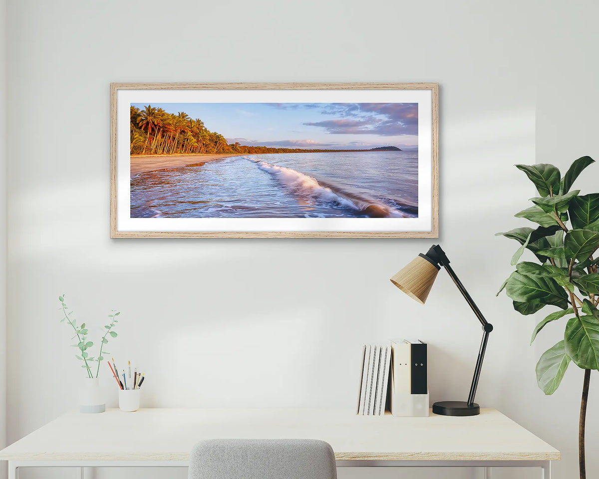 Four Mile Sunrise. Framed wall art print of Four Mile Beach, Port Douglas, with a timber frame hung above a home office desk. 