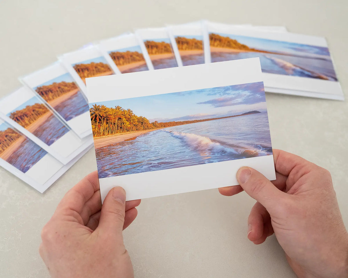 Four Mile Sunrise greeting card of sunrise over Four Mile Beach, Port Douglas, being held in front of other cards.
