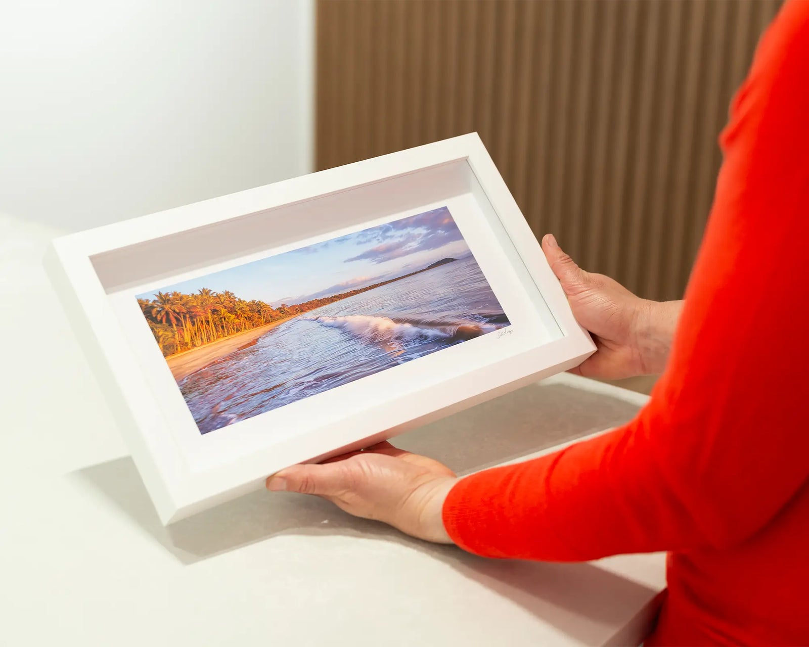 Framed artwork of a beach scene with palm trees and a calm sea at Four Mile Beach. 