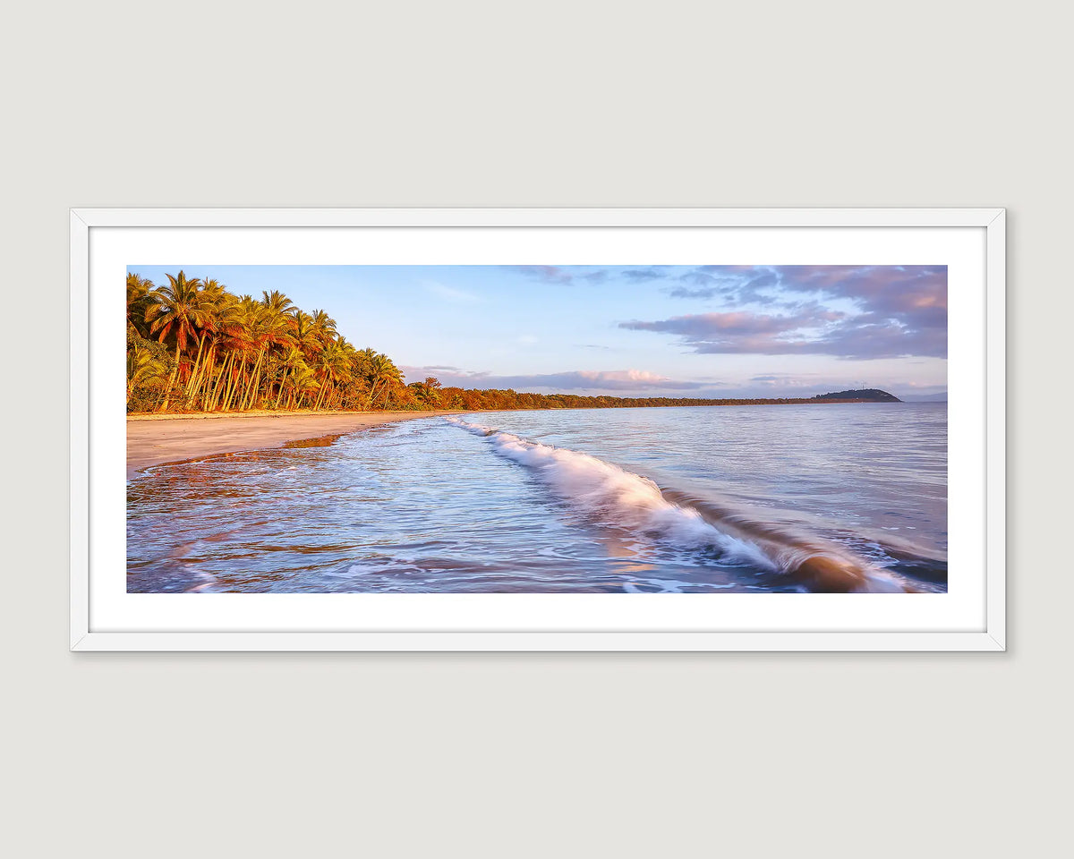 Framed artwork of a beach scene with palm trees and a calm sea at Four Mile Beach. 