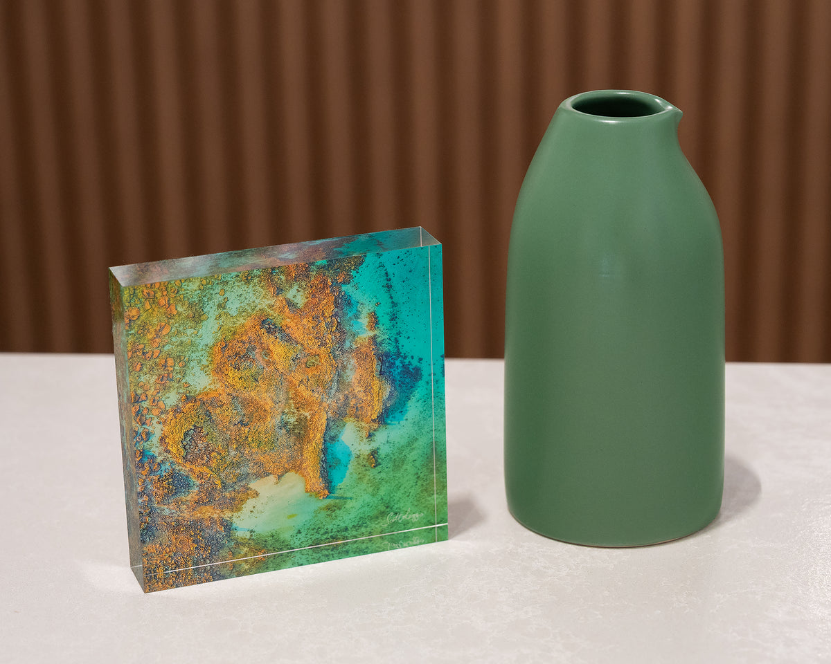 Fragment. Acrylic block aerial artwork James Price Point, The Kimberley, on desk styled with a small vase.