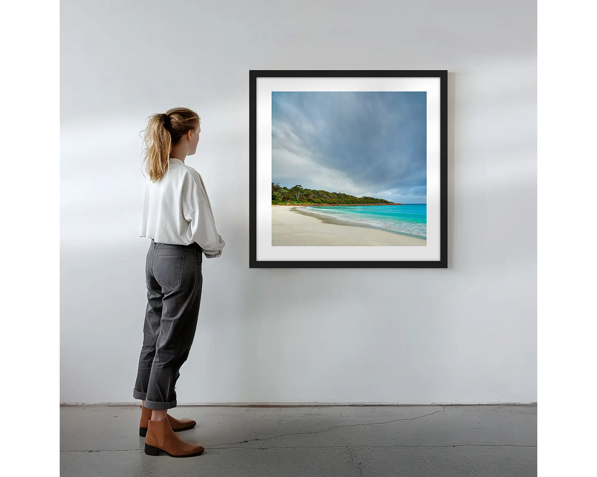 Geographe Calm. Wall art print with black frame featuring Geographe Bay Western Australia, hung on a wall with woman admiring.