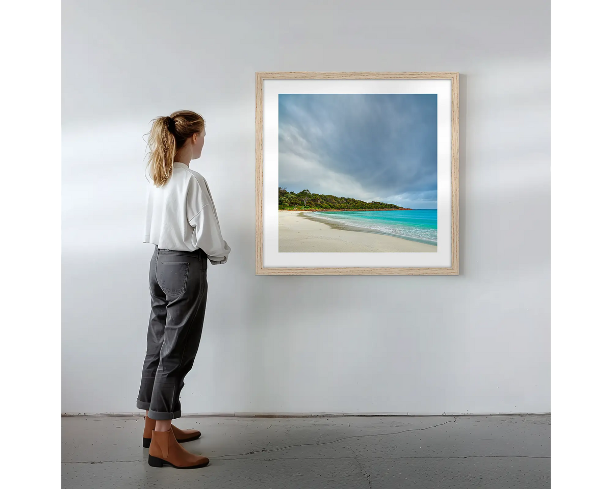 Geographe Calm. Wall art print with timber frame featuring Geographe Bay Western Australia, hung on a wall with woman admiring.
