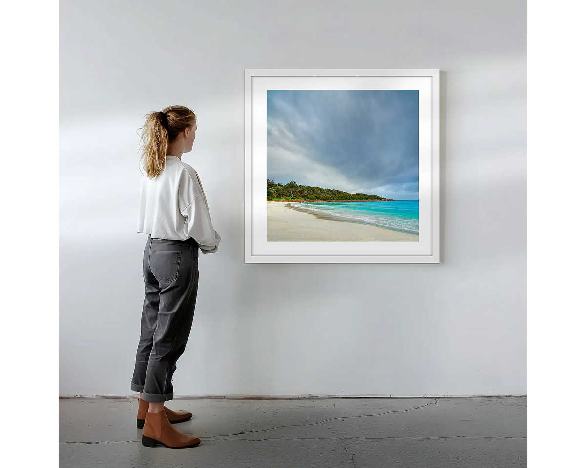 Geographe Calm. Wall art print with white frame featuring Geographe Bay Western Australia, hung on a wall with woman admiring.