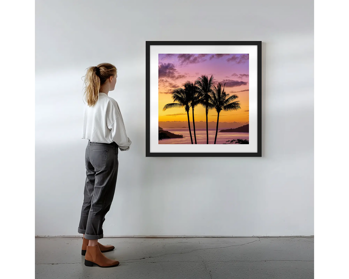Getaway.  Wall art print with black frame featuring Hamilton Island palm trees, hung on a wall with woman admiring.