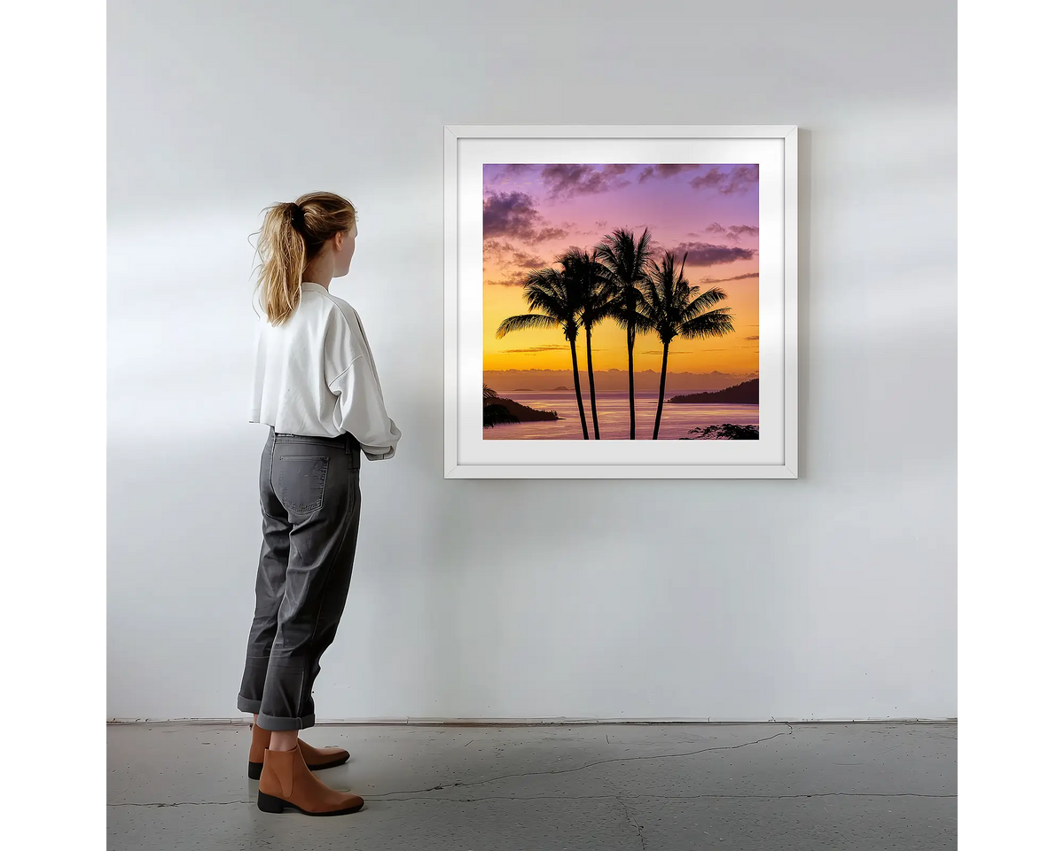 Getaway.  Wall art print with white frame featuring Hamilton Island palm trees, hung on a wall with woman admiring.
