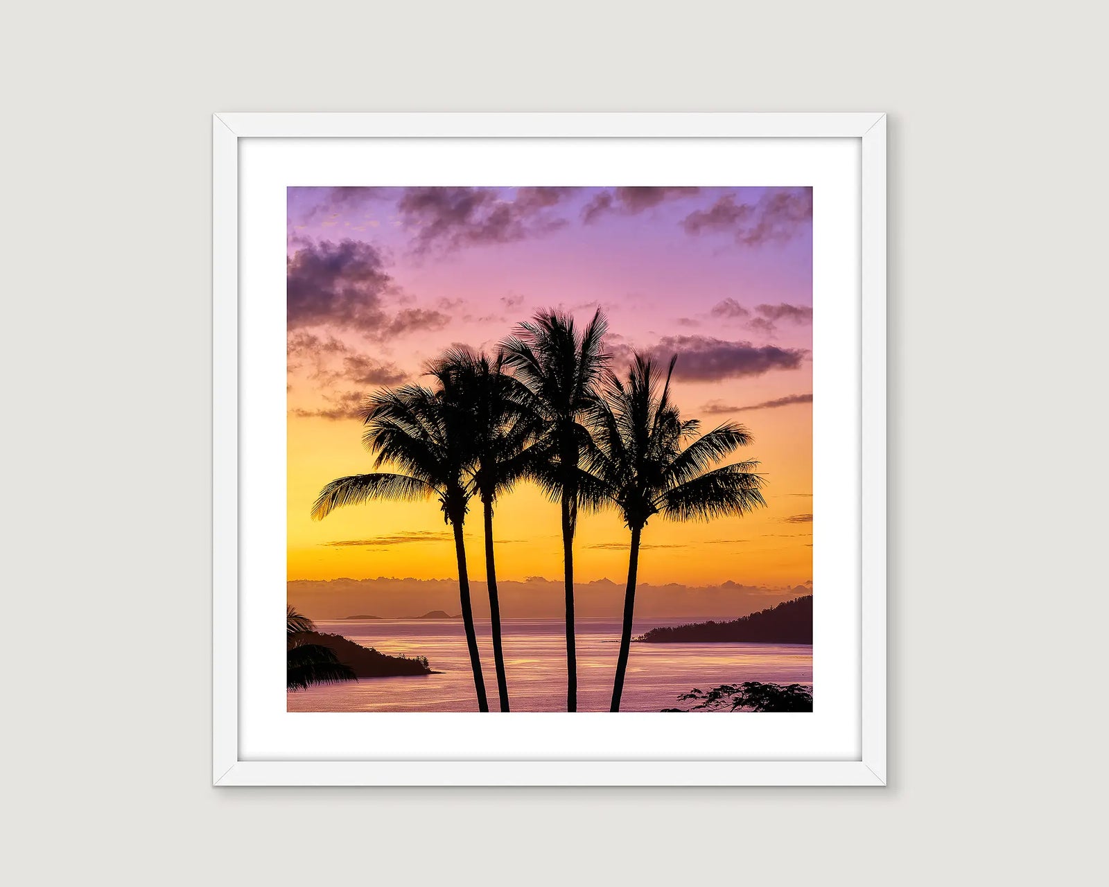 Framed coastal artwork of palm trees against a colorful sunset sky at Hamilton Island. 