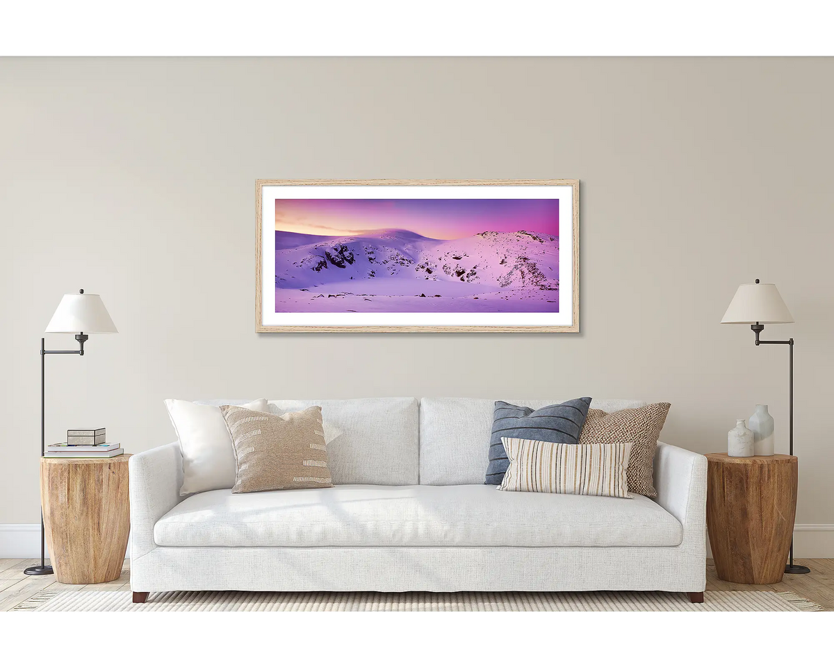 Glacial Landscape. Wall art print of a sunset over Blue Lake, Kosciuszko National Park, framed with a timber frame and hung above a couch. 