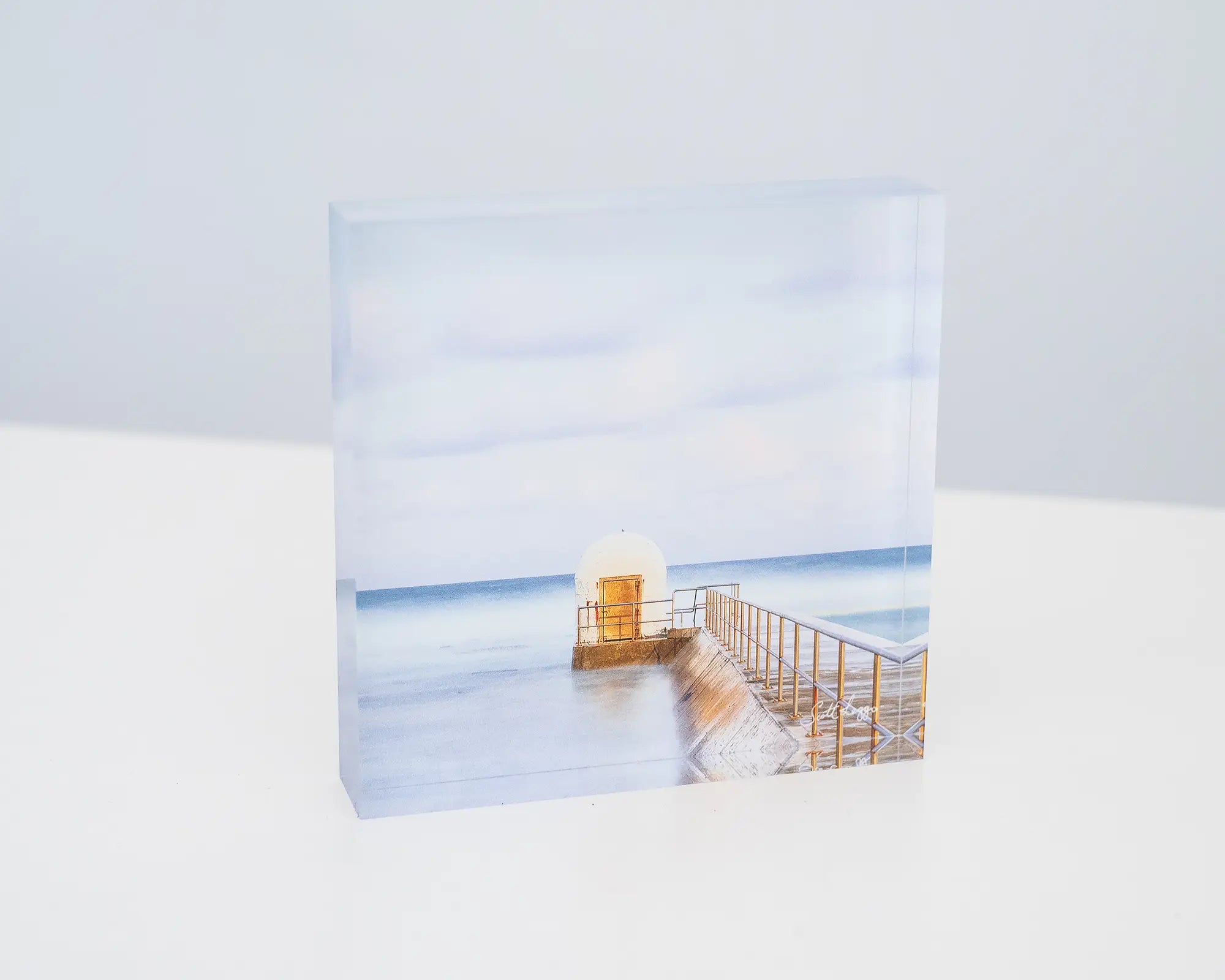 Golden Door. Acrylic block of dusk at Merewether Baths Newcastle, sitting on a desk.