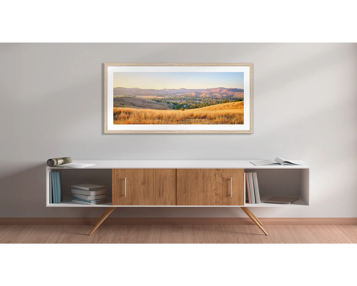 Golden Riverina. Wall art print with a timber frame, of a sunrise over Gundagai, hung above a side table. 