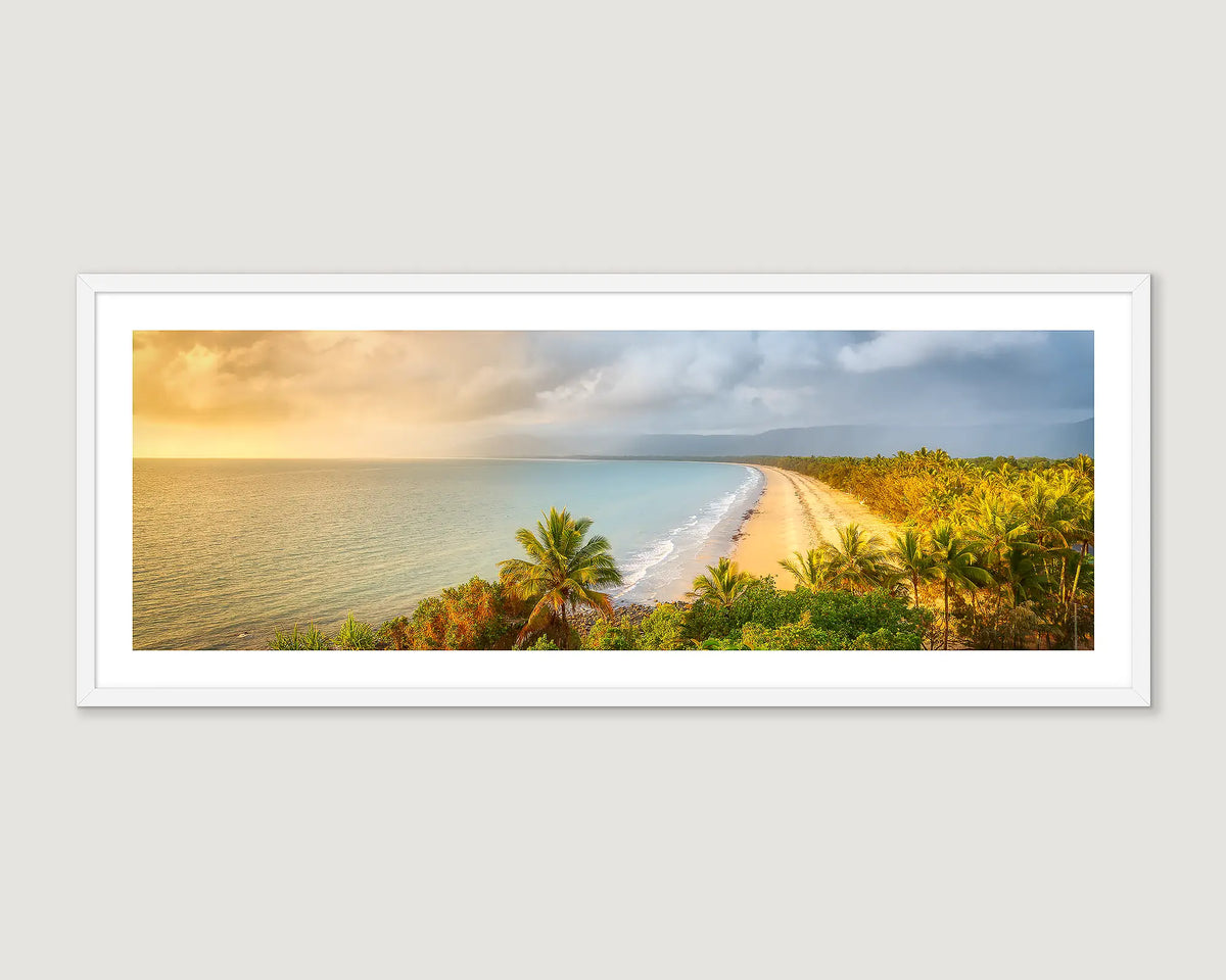 Framed photograph of a beach with palm trees and mountains at sunrise.