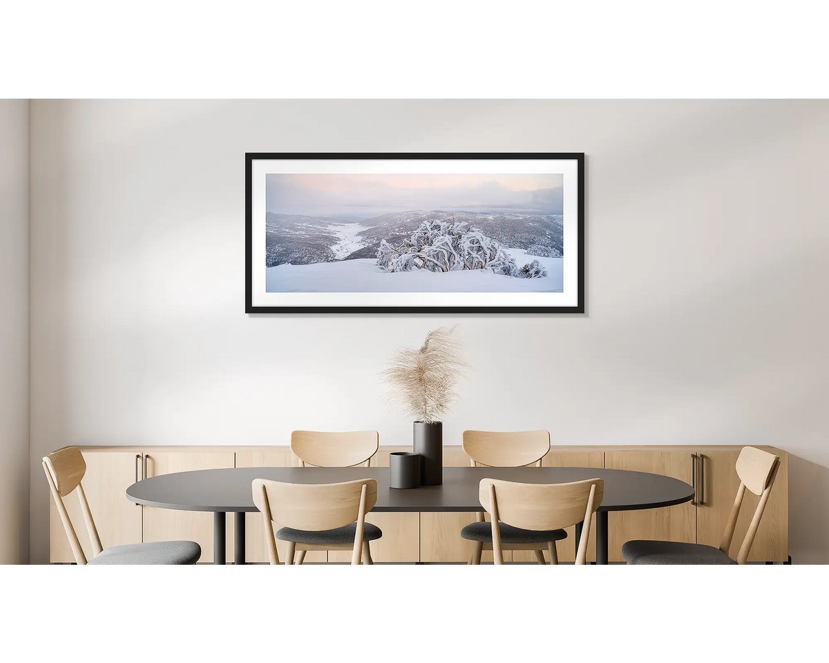 Guardian of the Valley. Wall art print of a snow gum overlooking a snow covered valley, framed in a black frame and hung on a dining room wall. 