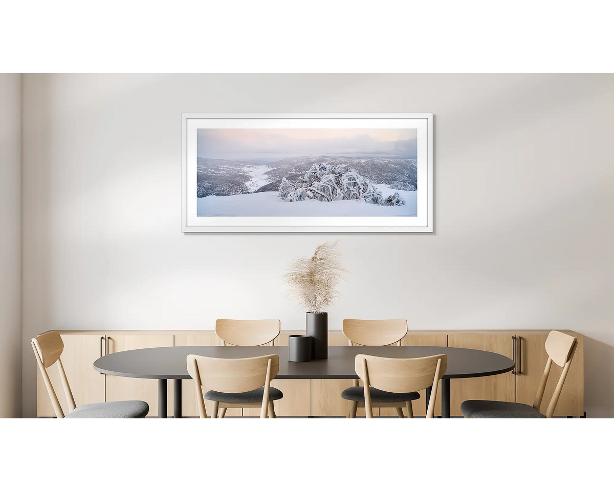 Guardian of the Valley. Wall art print of a snow gum overlooking a snow covered valley, framed in a white frame and hung on a dining room wall. 