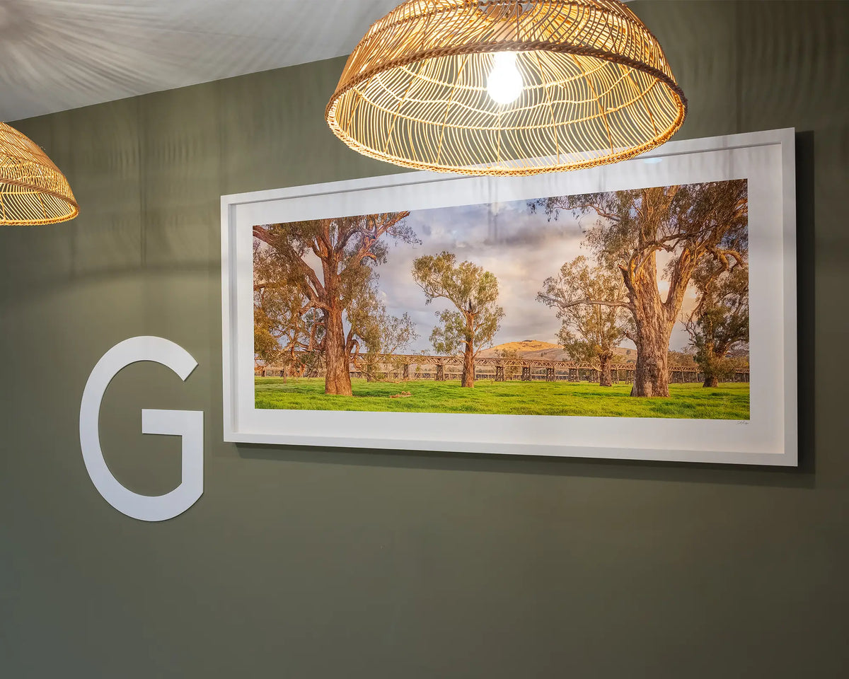 Gundagai Heritage. Historic bridges of Gundagai, with white frame hung on olive green wall, ground floor commercial space.