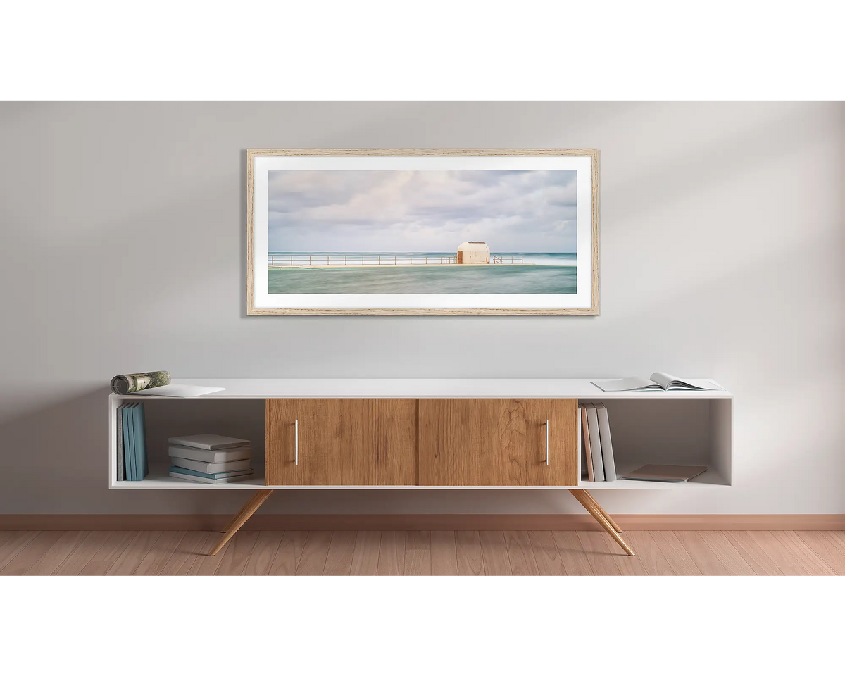 Hues of Merewether. Wall art print with a timber frame, of the pump house Merewether Baths, Newcastle, hung above a side table. 