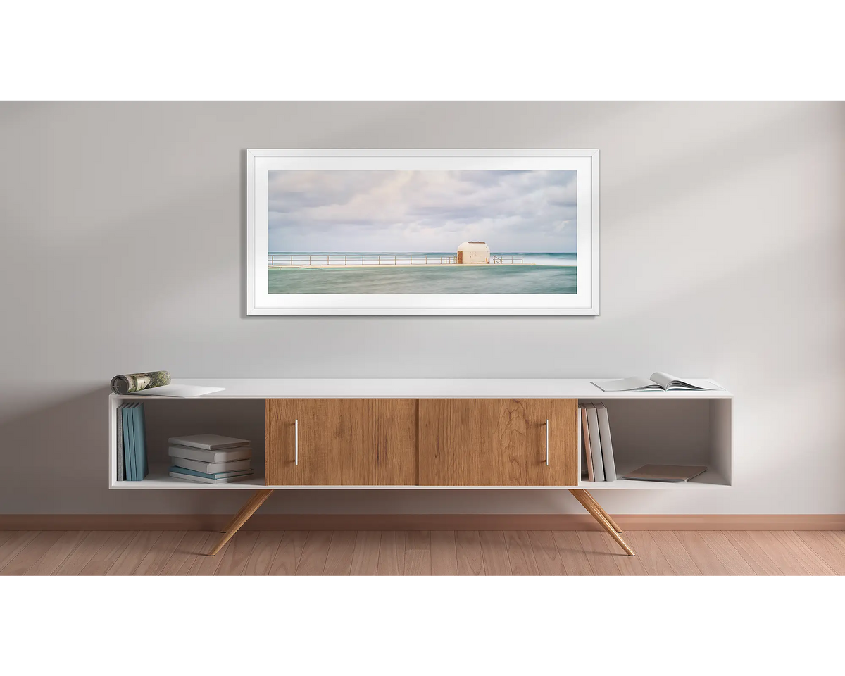 Hues of Merewether. Wall art print with a white frame, of the pump house Merewether Baths, Newcastle, hung above a side table. 