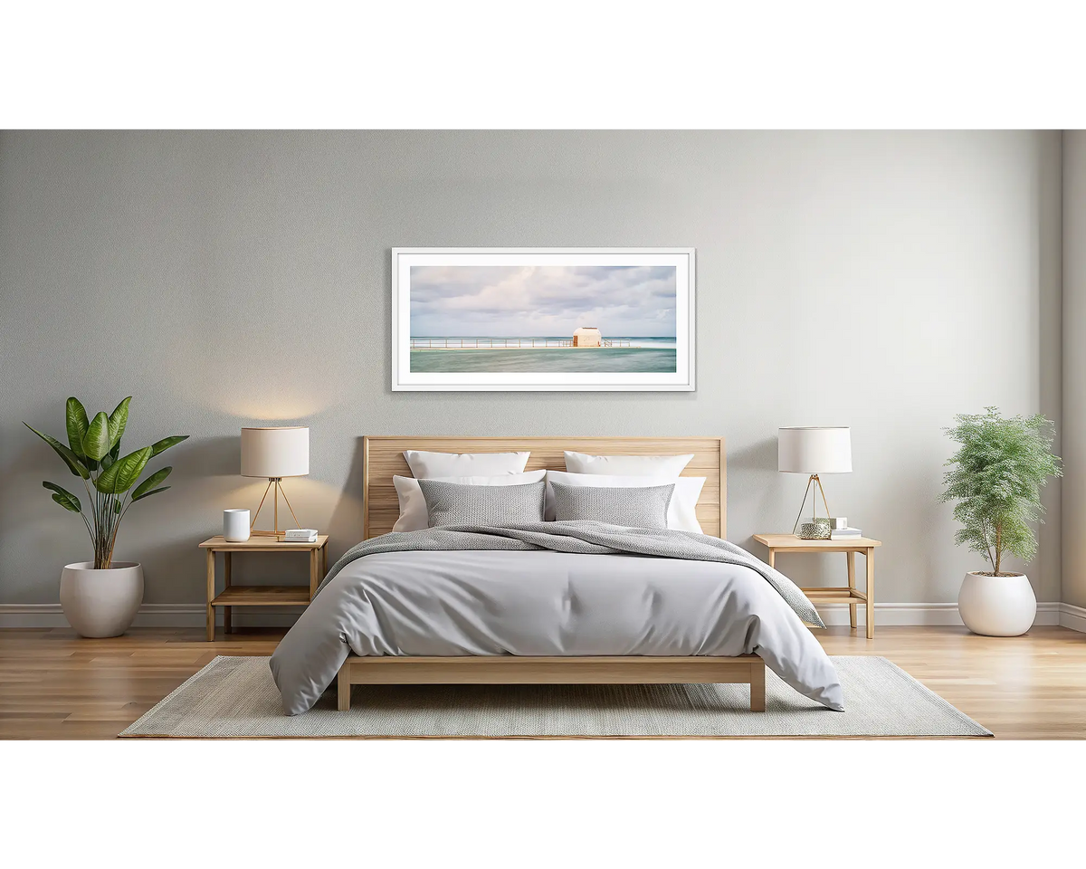 Hues of Merewether. Wall art print with a white frame, of the pumphouse, Merewether Baths, Newcastle, hung in a light filled bedroom. 