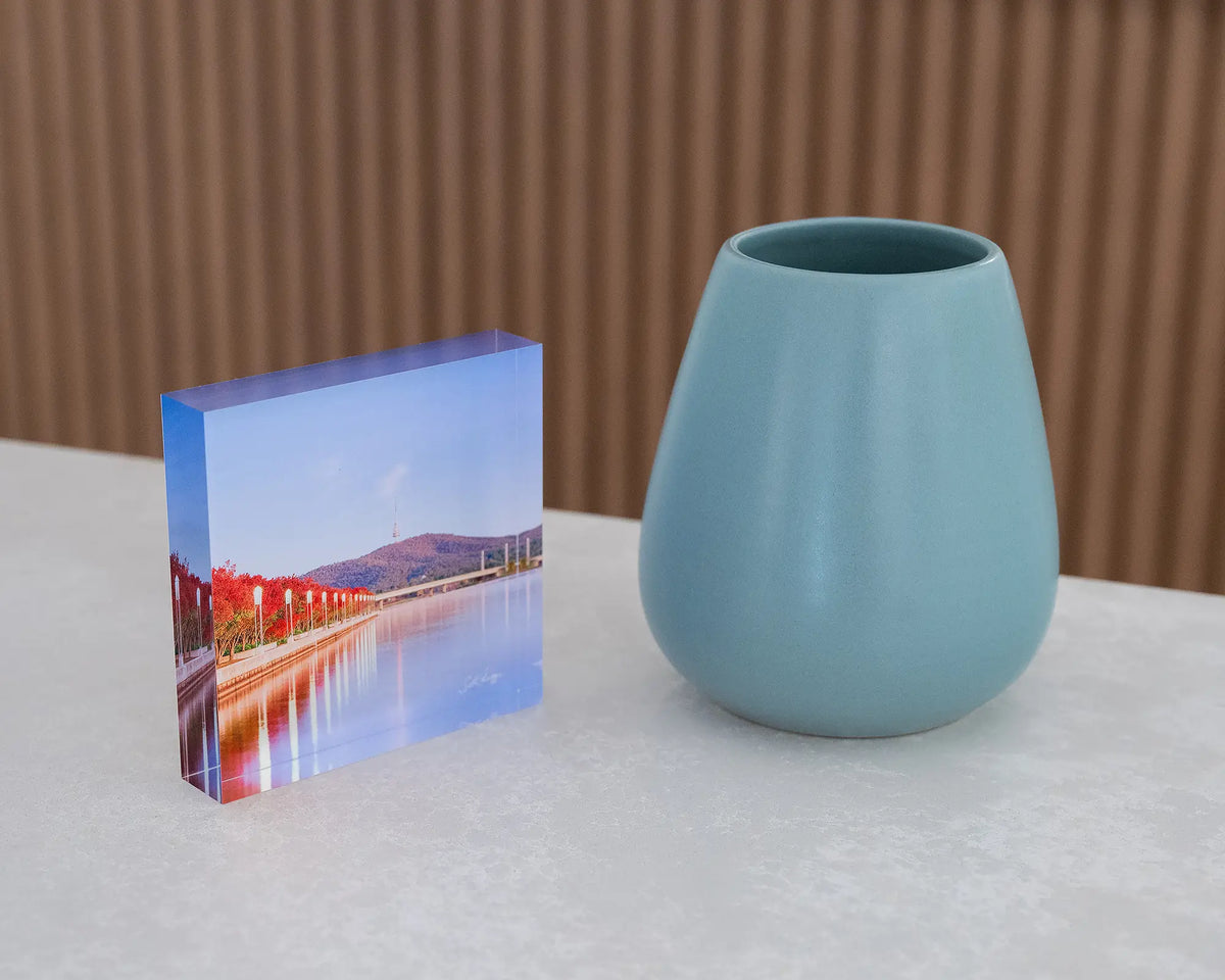 Impressions of Autumn. Acrylic block of autumn trees lining Lake Burley Griffin, Canberra, on desk styled with a small vase.