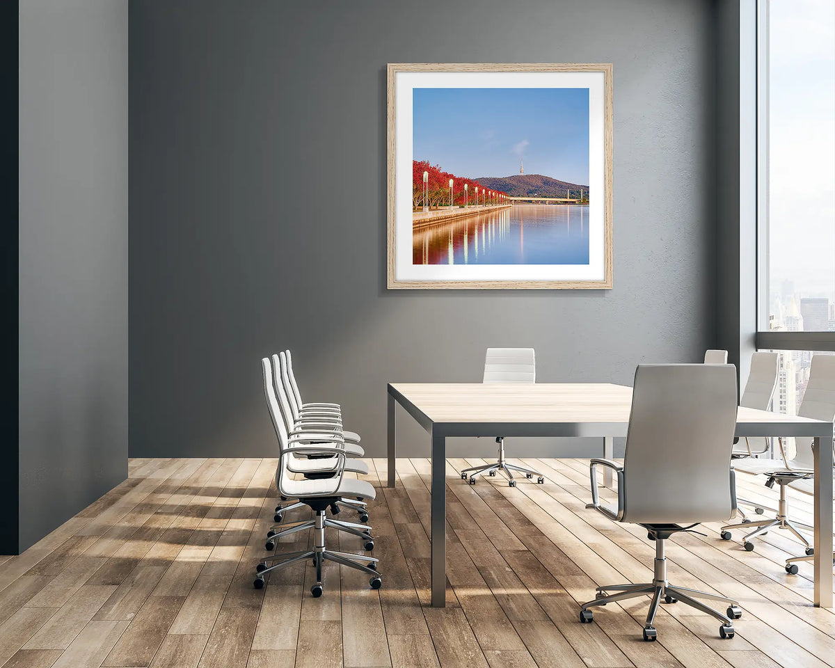 Impressions Of Autumn. Canberra artwork with timber frame, featuring red trees beside Lake Burley Griffin, hung on boardroom wall.
