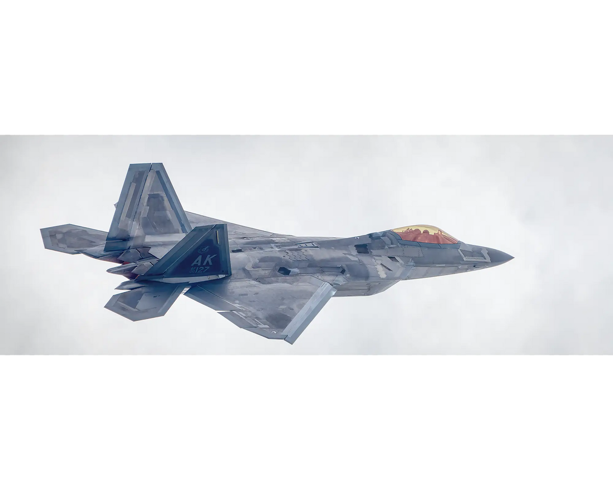 United States Air Force F-22 Raptor flying through clouds. 