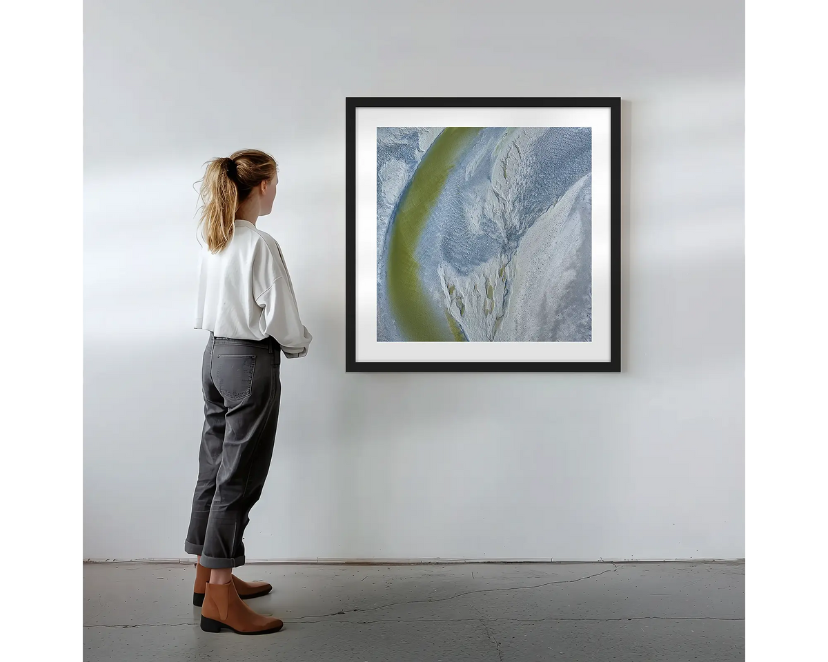 Journey to the Sea. Wall art print with black frame featuring an abstract aerial scene from the Kimberley, hung on a wall with woman admiring.