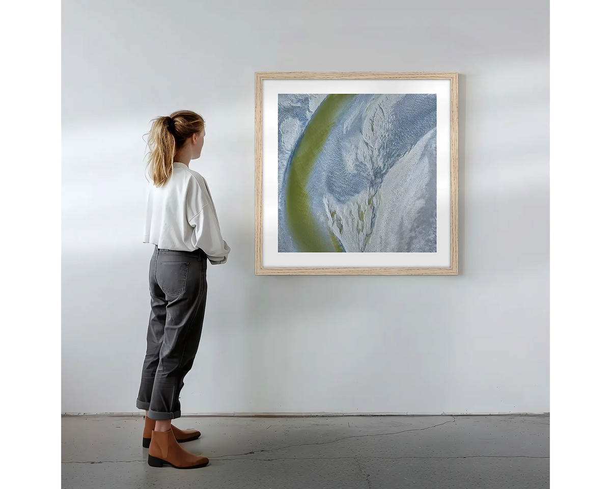 Journey to the Sea. Wall art print with timber frame featuring an abstract aerial scene from the Kimberley, hung on a wall with woman admiring.