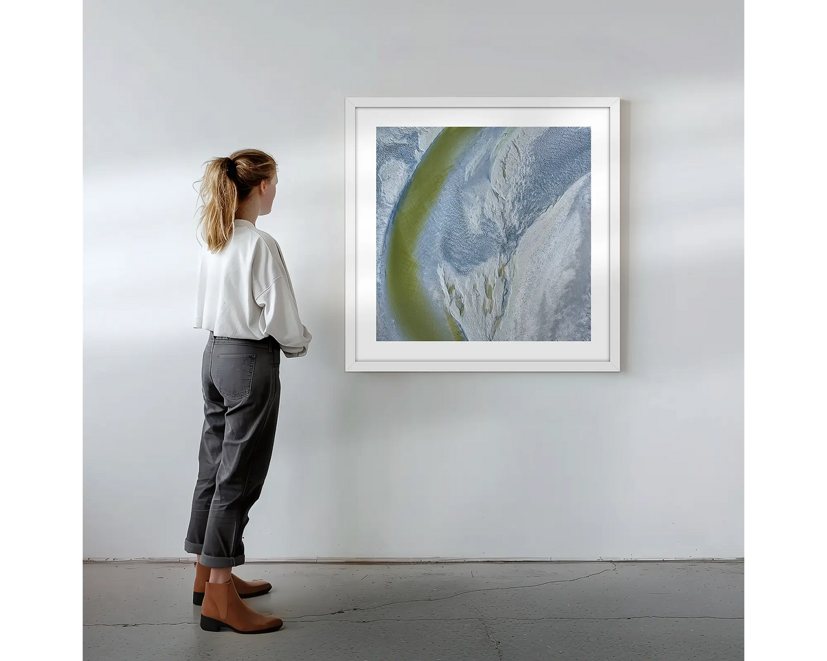 Journey to the Sea. Wall art print with white frame featuring an abstract aerial scene from the Kimberley, hung on a wall with woman admiring.
