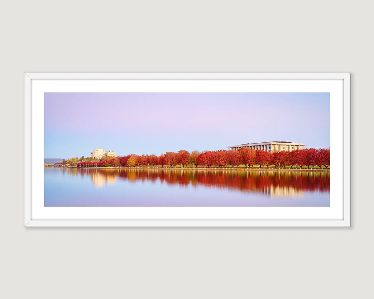 Framed wall art print of a sunset and trees turning red in autumn in front of the High Court and the Library on Lake Burley Griffin. 