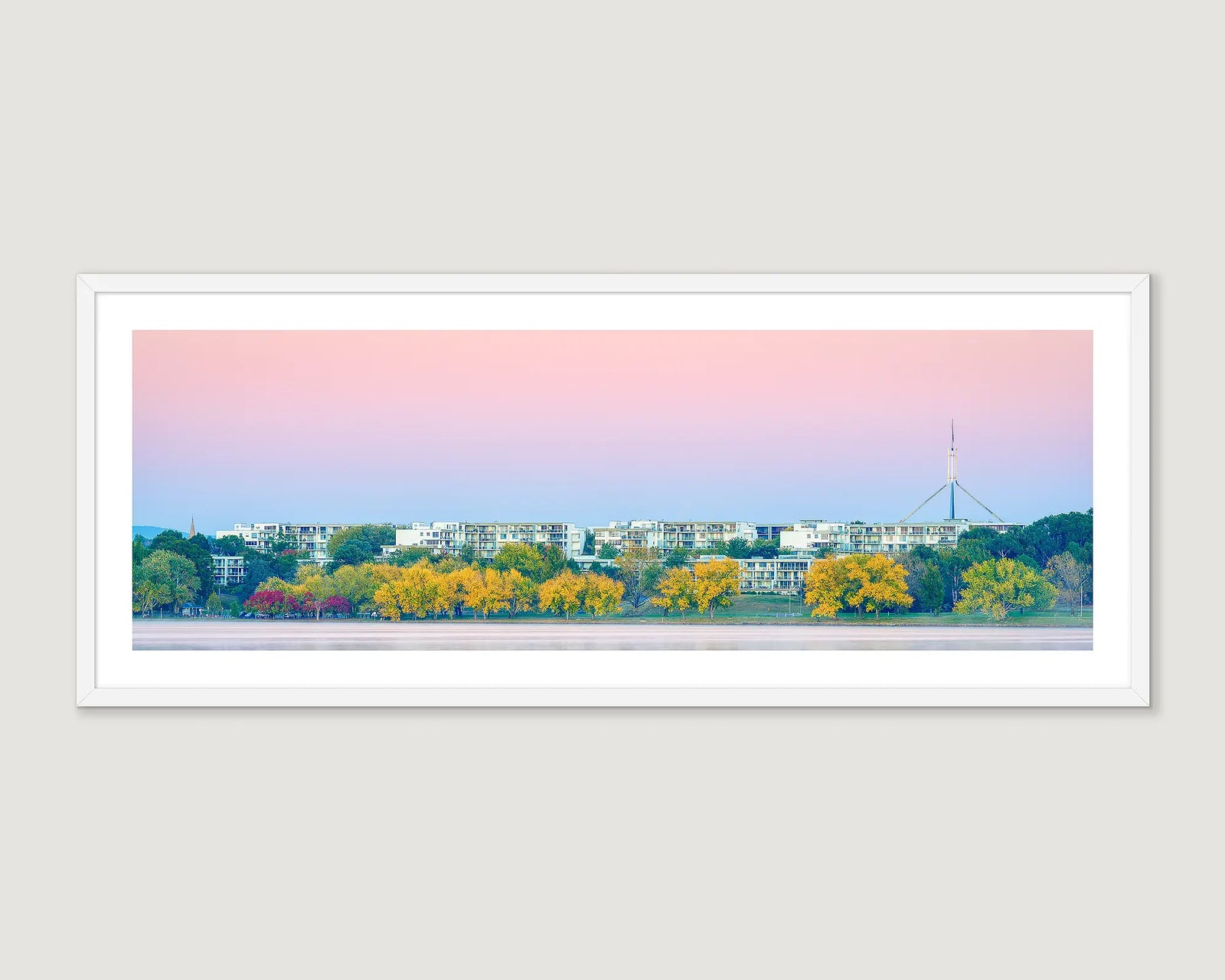 Framed wall art print of the Landmark Apartments on Lake Burley Griffin with trees turning yellow in autumn and Parliament House in view. 
