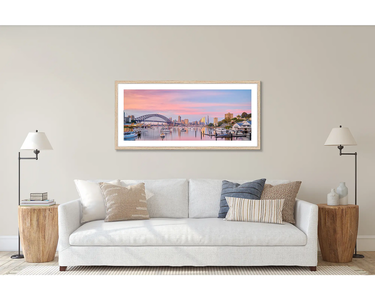 Lavender Sunrise. Wall art print of a sunrise over Lavender Bay, Sydney, framed in a Tasmanian Oak frame and hung above a couch. 