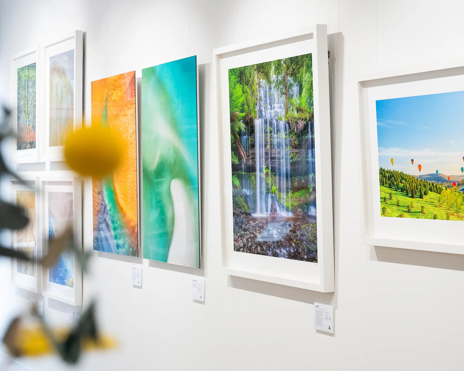 Framed photographic print of Russell Falls flowing with water over layers of rocks with rainforest plants.