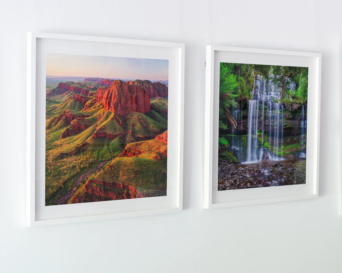 Layers. Russell Falls waterfall wall art framed in white frame hanging on wall in gallery.