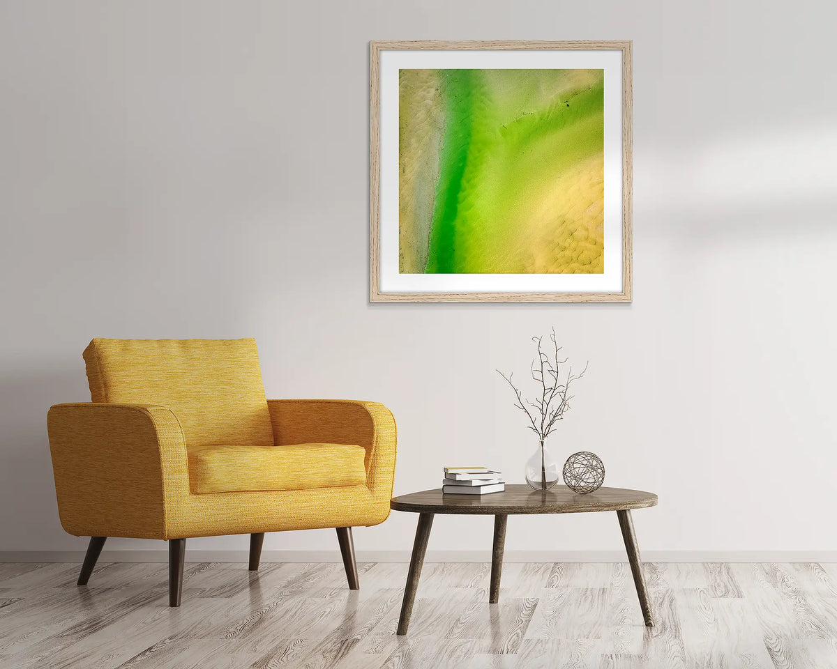 Lemon and Lime. Abstract, aerial wall art of Durras, framed in a Tasmanian Oak frame and hung above a chair.