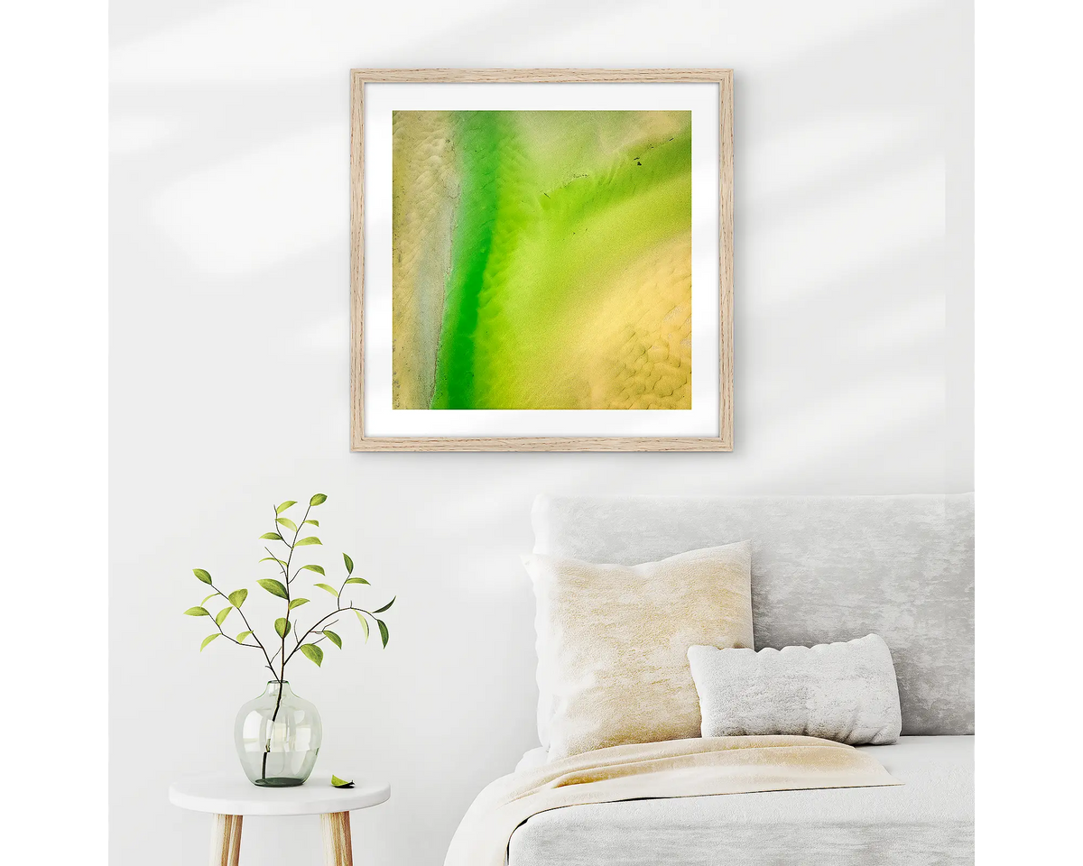Lemon and Lime. Abstract wall art print of Durras Lake, framed in a timber frame and hung above a bed. 