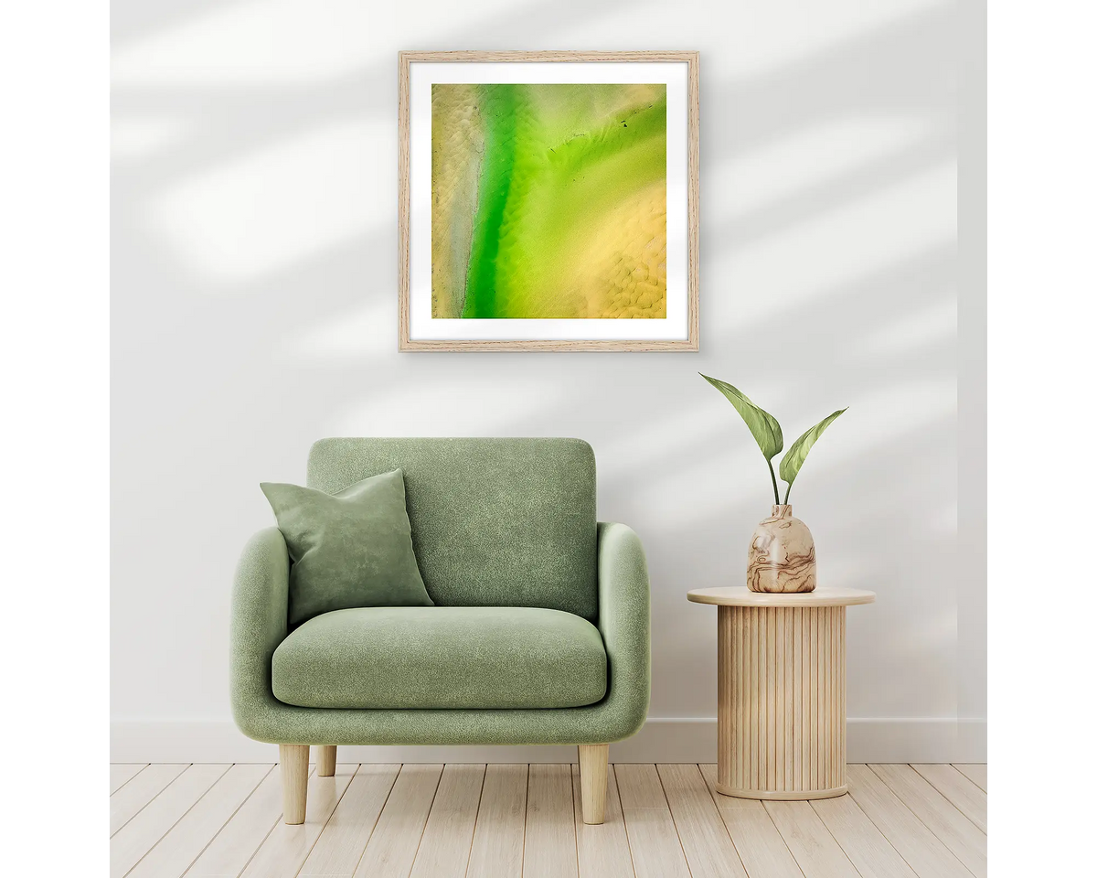 Lemon and Lime. Abstract wall art print of Durras Lake, framed in a timber frame and hung above a single seat couch. 