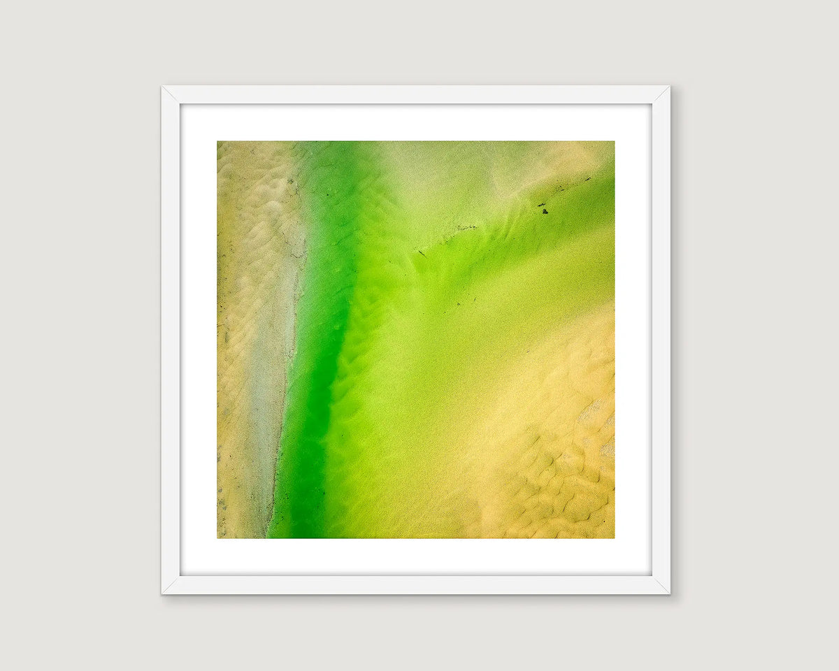 Framed abstract photograph of water and sand in green and yellow colours.