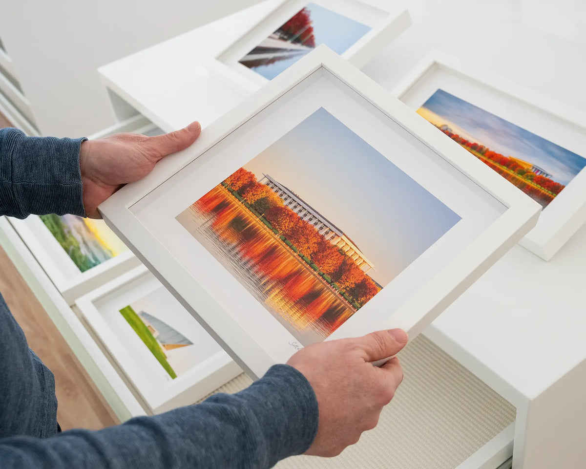 Library Reds. National Library of Australia small framed print with white frame hand held in the gallery.