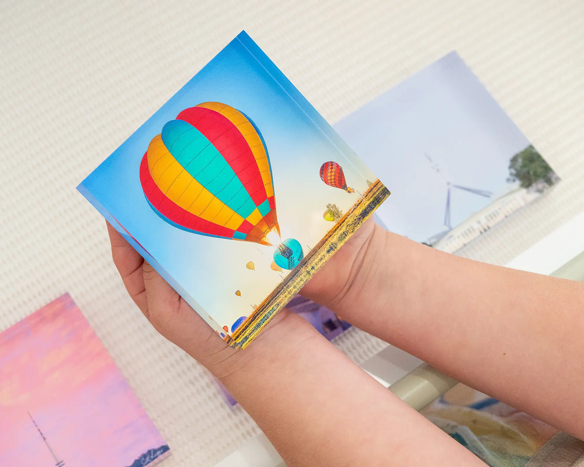 Lift. Acrylic block of the Canberra Balloon Spectacular, being held in child&#39;s hands.