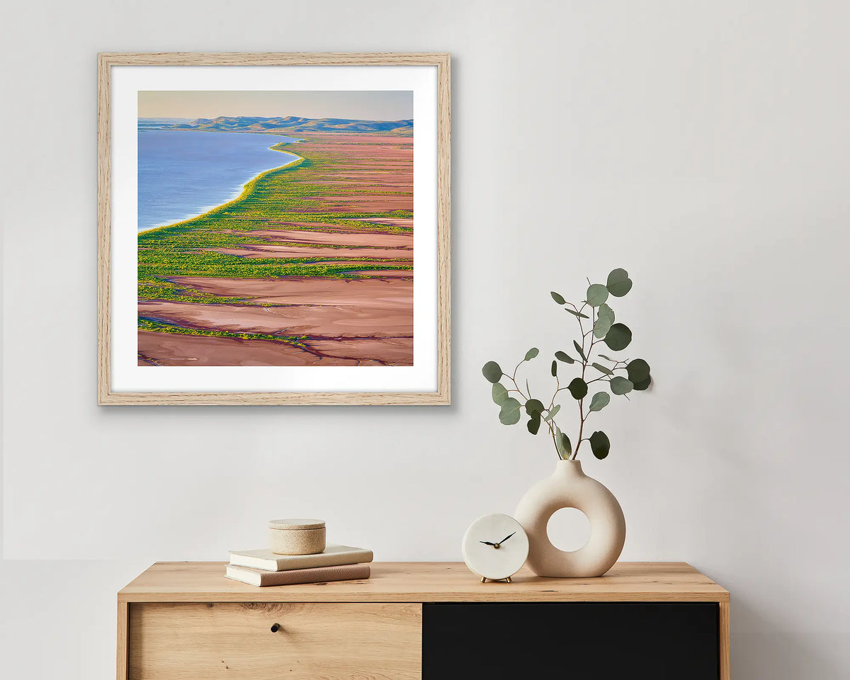 Lighting the Gulf. Wall art print with timber frame of sunset over Cambridge Gulf, the Kimberley, hung above a small side table.